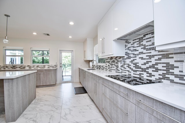 kitchen with black electric stovetop, white cabinetry, decorative light fixtures, and backsplash