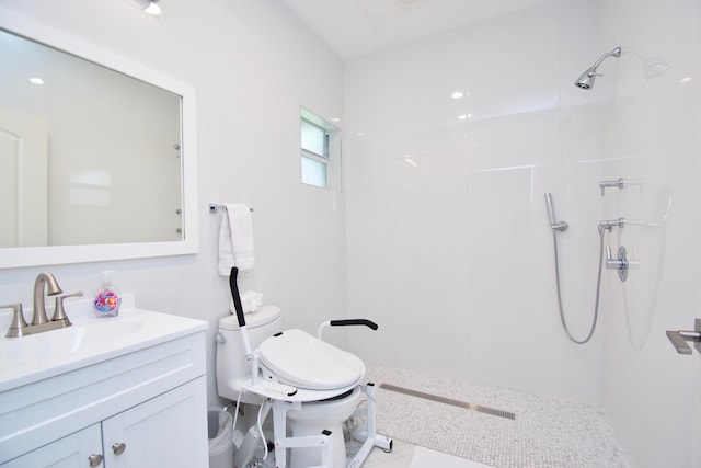 bathroom with vanity, a tile shower, and toilet