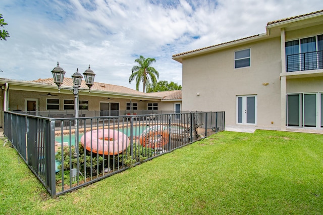 back of house featuring a fenced in pool and a yard