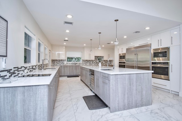 kitchen featuring a large island, white cabinetry, tasteful backsplash, sink, and built in appliances