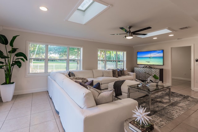 living room featuring ceiling fan, light tile patterned flooring, ornamental molding, and a skylight