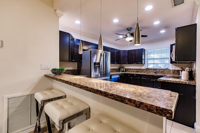 kitchen featuring a kitchen bar, appliances with stainless steel finishes, kitchen peninsula, ceiling fan, and pendant lighting