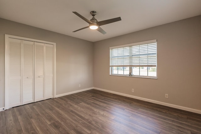 unfurnished bedroom featuring ceiling fan, a closet, and dark wood-type flooring