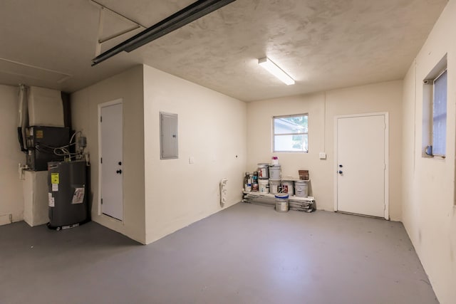 garage featuring electric panel, water heater, and heating unit