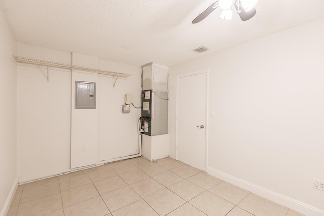 tiled empty room with electric panel, ceiling fan, and a textured ceiling