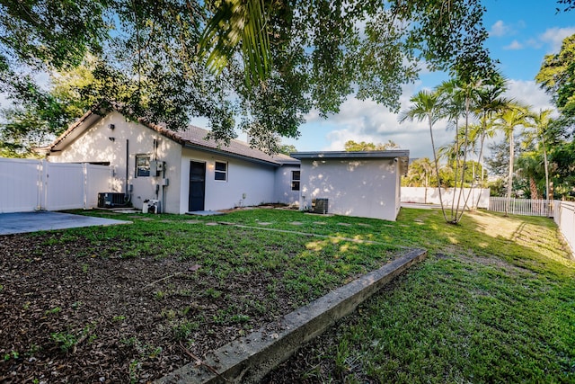 back of property featuring central AC and a lawn