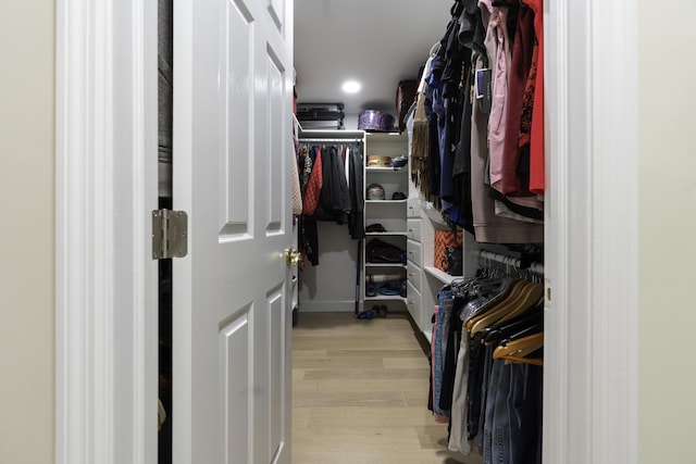 walk in closet with light hardwood / wood-style floors