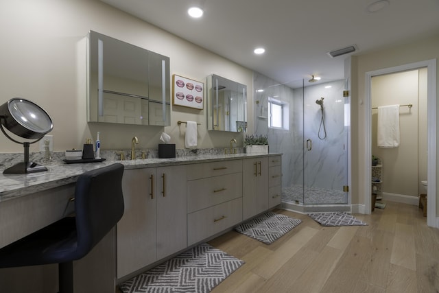 bathroom featuring a shower with shower door, hardwood / wood-style floors, and vanity