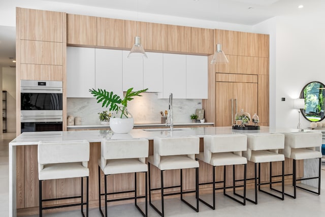 kitchen featuring double oven, a kitchen bar, decorative backsplash, and a spacious island