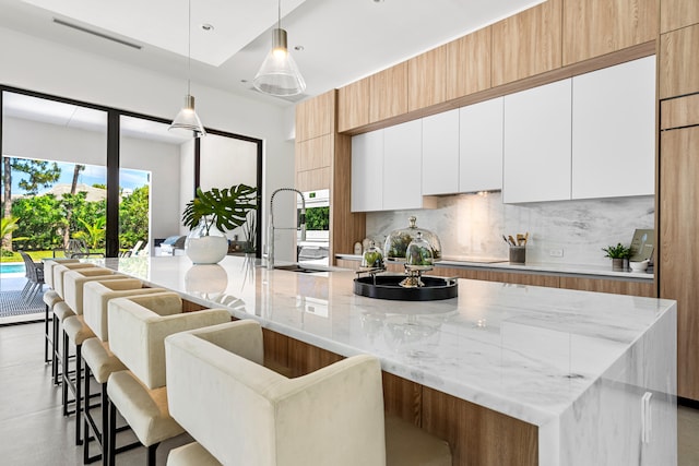 kitchen with white cabinets, a kitchen breakfast bar, a large island, and a wealth of natural light