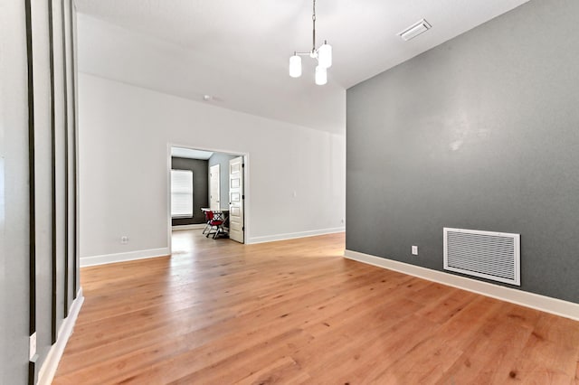 unfurnished room with a notable chandelier and light wood-type flooring