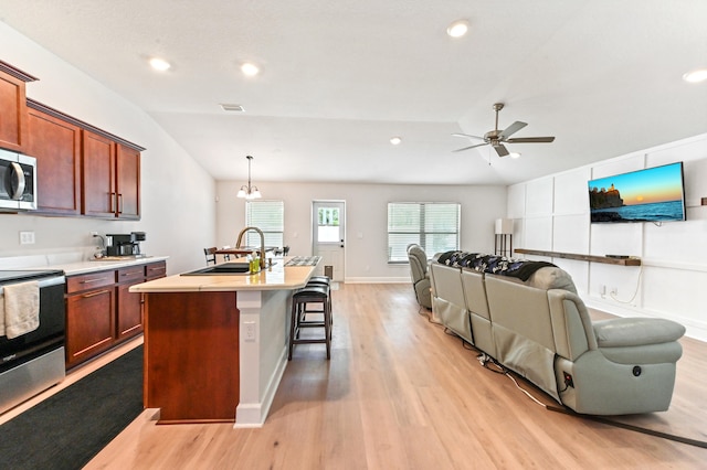 kitchen with sink, stainless steel appliances, pendant lighting, lofted ceiling, and light wood-type flooring