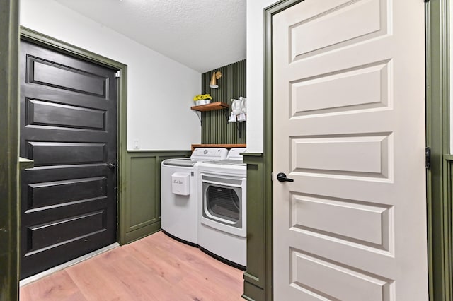 laundry area featuring washer and dryer, a textured ceiling, and light hardwood / wood-style flooring