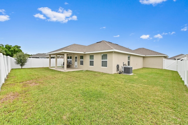 rear view of property featuring a patio, a yard, and central AC