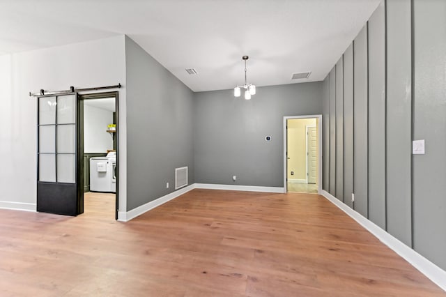 empty room with light hardwood / wood-style floors and an inviting chandelier