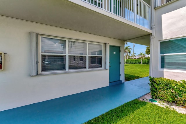 property entrance with a balcony and a yard