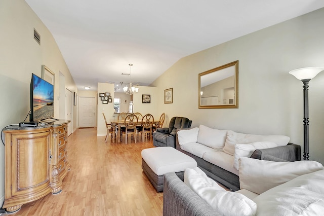 living room featuring light hardwood / wood-style flooring, a chandelier, and vaulted ceiling