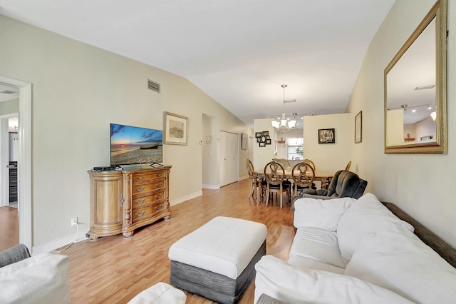 living room featuring hardwood / wood-style floors, an inviting chandelier, and vaulted ceiling