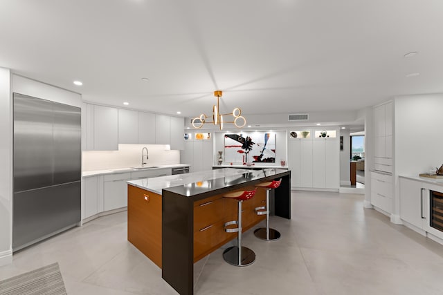 kitchen featuring decorative light fixtures, white cabinets, sink, a center island, and a breakfast bar area