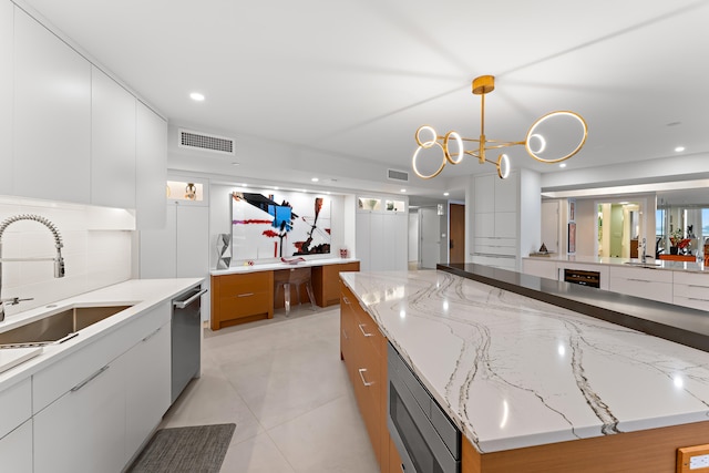 kitchen featuring sink, decorative light fixtures, white cabinetry, and light tile patterned floors