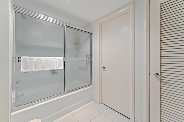 bathroom featuring tile patterned flooring and bath / shower combo with glass door