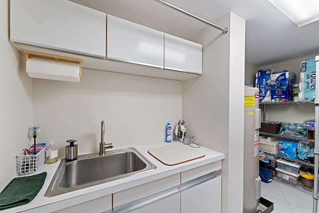 kitchen with electric water heater, white cabinetry, sink, and light tile patterned floors