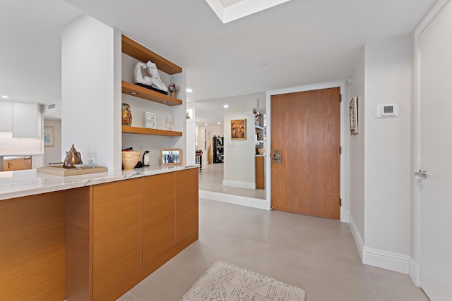 kitchen with light stone counters, a skylight, and light tile patterned floors