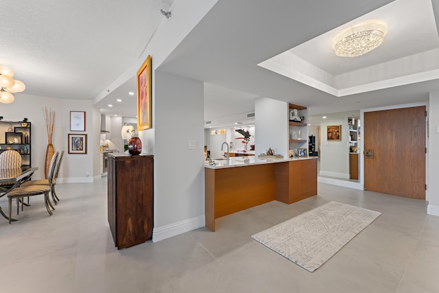 kitchen featuring sink, tile patterned floors, kitchen peninsula, and a tray ceiling