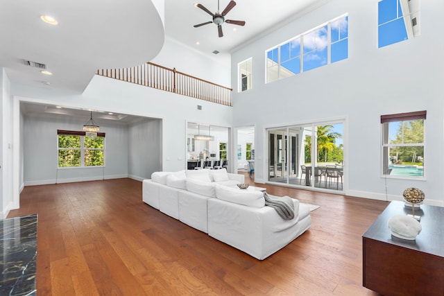 living room with hardwood / wood-style floors, ceiling fan, a towering ceiling, and a wealth of natural light