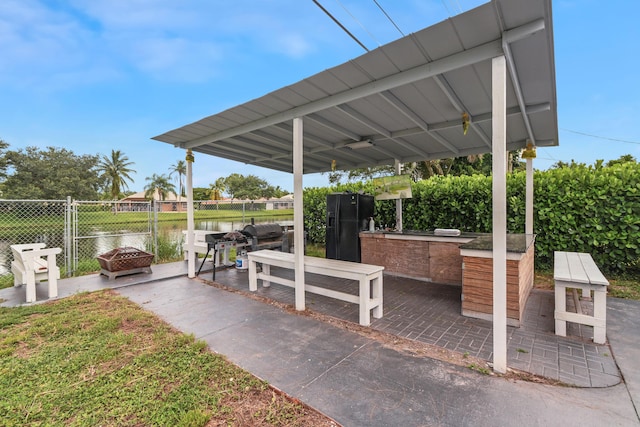 view of patio / terrace featuring a water view, a bar, and a fire pit