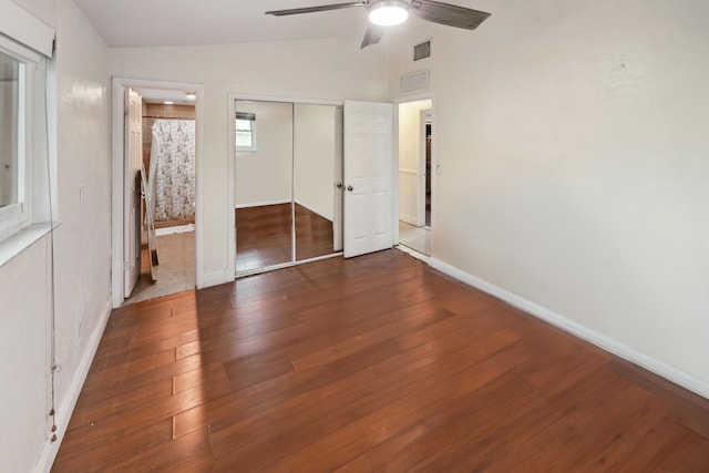 unfurnished bedroom with ceiling fan, dark wood-type flooring, ensuite bathroom, and vaulted ceiling