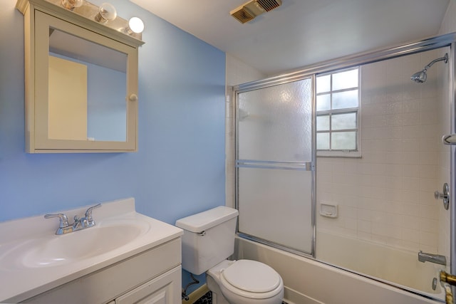 full bathroom with enclosed tub / shower combo, vanity, and toilet