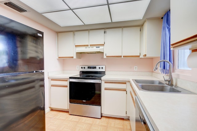 kitchen featuring electric stove, black refrigerator, white cabinets, and sink