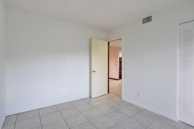 unfurnished bedroom featuring light tile patterned flooring, a textured ceiling, and a closet