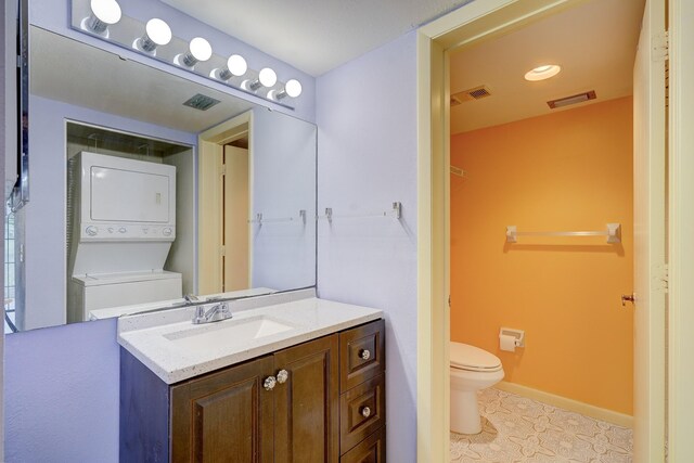 bathroom with vanity, stacked washer and clothes dryer, and toilet