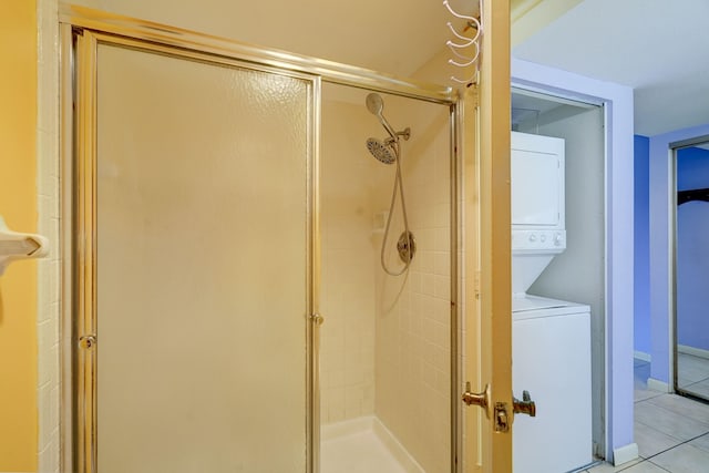 bathroom featuring stacked washer / dryer, an enclosed shower, and tile patterned flooring