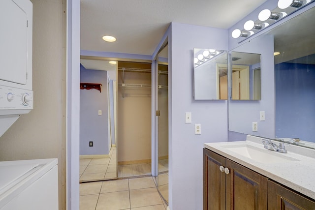 bathroom featuring stacked washer and dryer, vanity, and tile patterned flooring