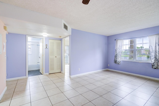 unfurnished room with light tile patterned flooring and a textured ceiling