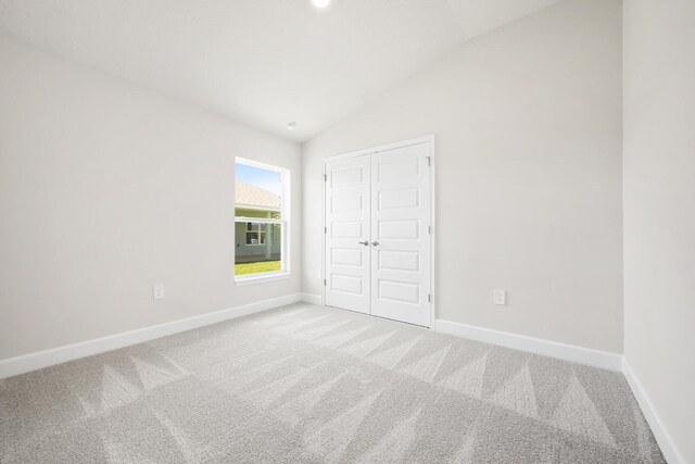 unfurnished bedroom featuring carpet flooring, a closet, and vaulted ceiling