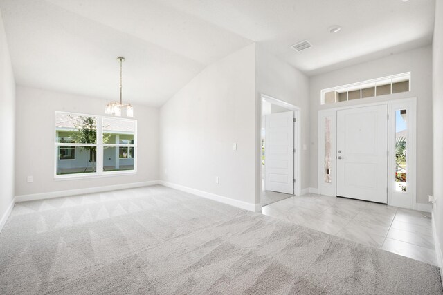 foyer featuring a wealth of natural light, light colored carpet, lofted ceiling, and an inviting chandelier