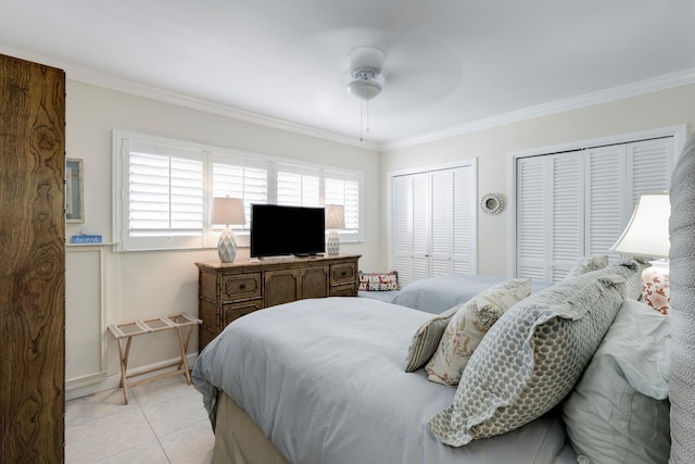 tiled bedroom with ceiling fan, two closets, and ornamental molding