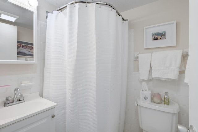 bathroom with toilet, vanity, backsplash, tile walls, and walk in shower