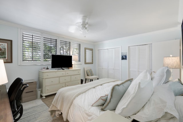 tiled bedroom with ceiling fan, ornamental molding, and two closets