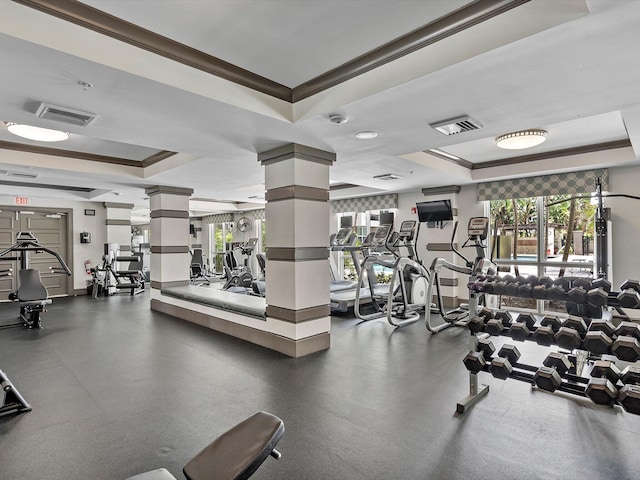 workout area featuring ornamental molding, decorative columns, and a tray ceiling