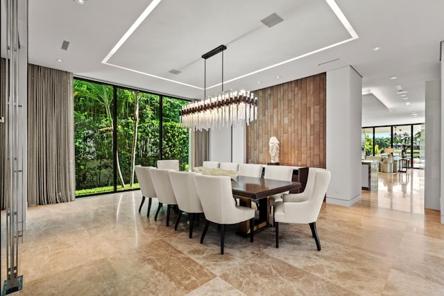 dining area featuring wooden walls, an inviting chandelier, and floor to ceiling windows