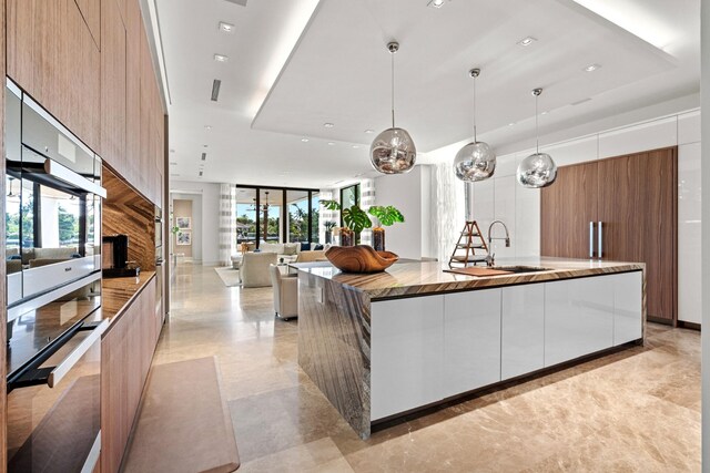 kitchen with hanging light fixtures, sink, a wealth of natural light, and a spacious island