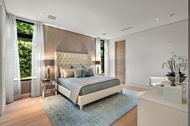 bedroom featuring floor to ceiling windows, multiple windows, and light wood-type flooring