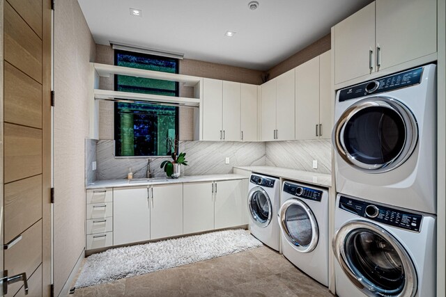 clothes washing area featuring cabinets, stacked washer and dryer, sink, and washer and clothes dryer