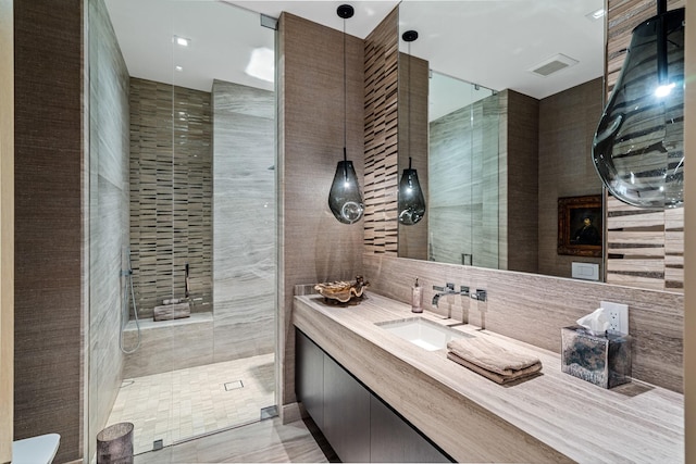 bathroom with tile walls, vanity, and a shower with door