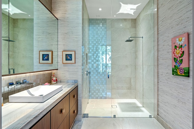 bathroom featuring a shower with door, vanity, and tile walls